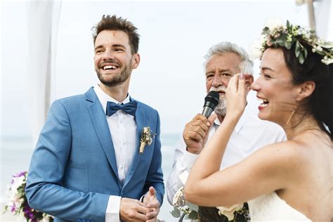Tematické foto: rečník prednášajúci svadobný príhovor, hostia počúvajúci a usmievajúci sa novomanželia