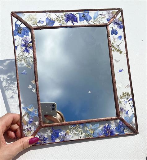 Ukážka ozdobeného zrkadla s umelými kvetmi na ráme.