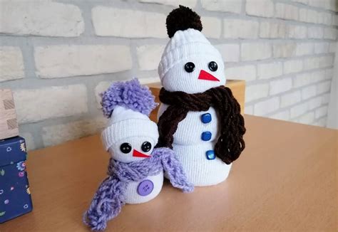 Malí snehuliaci vyrobení z vatových tampónov a tyčiniek na drevenej podložke.