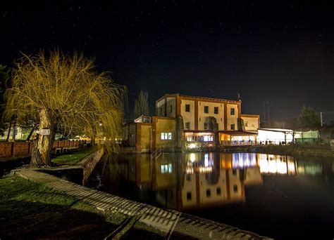 Panoramatický pohľad na Mlyn u Anastázie s nezamŕzajúcim jazierkom v popredí a romantickým osvetlením budovy