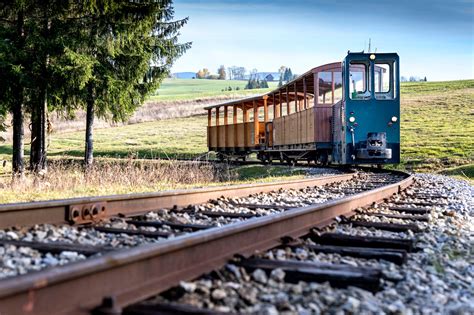 Fotografia: Oravská lesná železnica s vlakom prechádzajúcim cez lesnú krajinu v zime alebo panoramatický výhľad z vyhliadkovej veže na Sedle Beskyd.