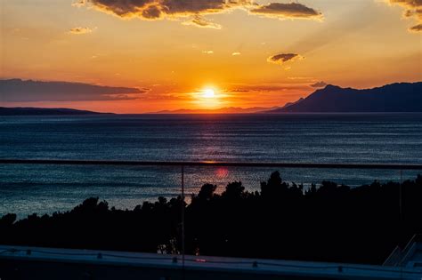 Silueta človeka hľadiaceho na oblohu pri západe slnka s jemnými oblakmi