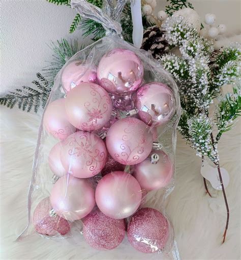 Detailne zábery na rôzne ružové a strieborné vianočné ozdoby vrátane gúľ, hviezd a figúrok.