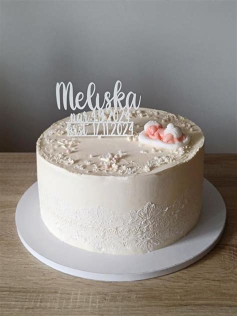 biela krstinová torta s jemnou modrou stužkou a kvetmi
