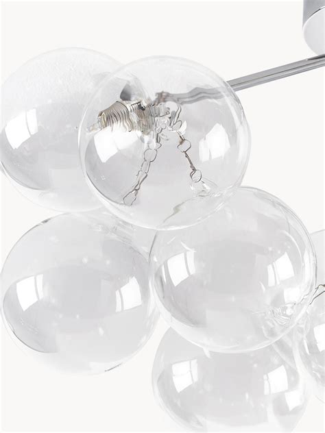 Minimalisticky ozdobená biela breza v interiéri s jemnými sklenenými guľami a LED osvetlením