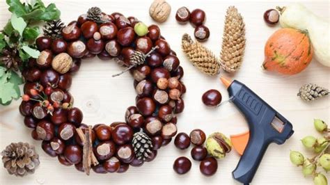 fotografia hotového jesenného venca z gaštanov zdobeného listami a šiškami