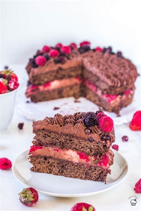 Dvojposchodová torta s čokoládovým a malinovým krémom, ozdobená čerstvým ovocím a čokoládovými tyčinkami.