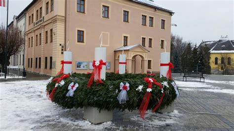 Záber na veľký adventný veniec na námestí počas rozsvecovania sviece s vianočnou výzdobou v pozadí