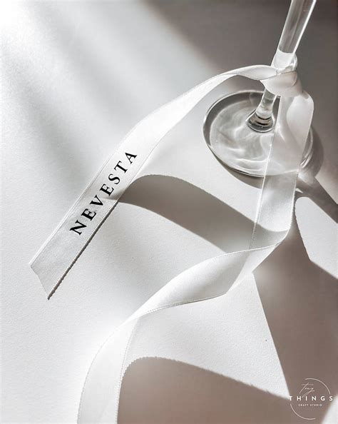 Detail fotografie bielej saténovej sukničky na krstovej sviečke.