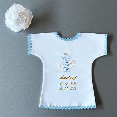 Bavlnená krstová košieľka s detailnou výšivkou bieleho anjelika a personalizovaným textom.