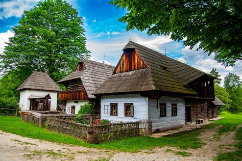 Ilustrácia slovenskej dediny s tradičnými drevenými domami a krojovanými postavami