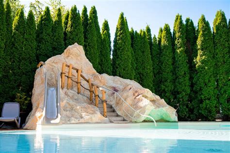 Pohľad na letnú terasu pri jazierku s vodopádom v areáli reštaurácie