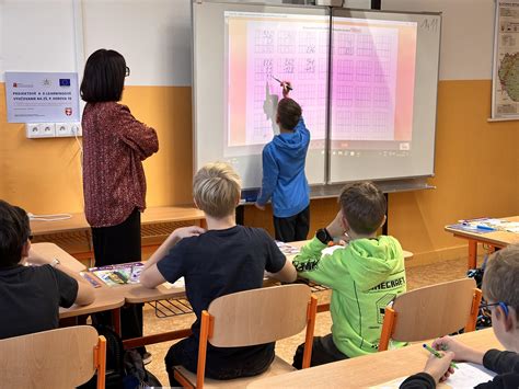 Študenti venujú kvetiny triednej učiteľke pri tabuli