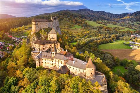 Pohľad na Oravský hrad z diaľky, zdôrazňujúci jeho polohu na skale nad riekou Orava.
