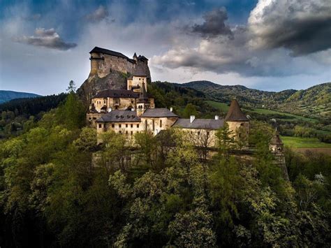 Svadobný pár fotografovaný v exteriéri Oravského hradu s dominantnou architektúrou v pozadí.