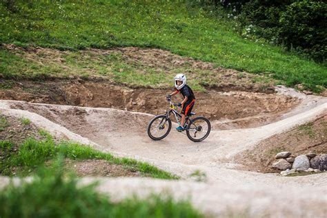 Deti jazdiace na bicykloch a kolobežkách na pumptrack dráhe