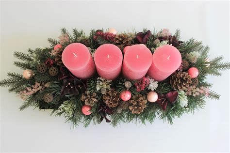 podlhovastý adventný veniec vyrobený z pohárov s vodou, ihličím, šiškami a štyrmi sviečkami na drevenom podnose