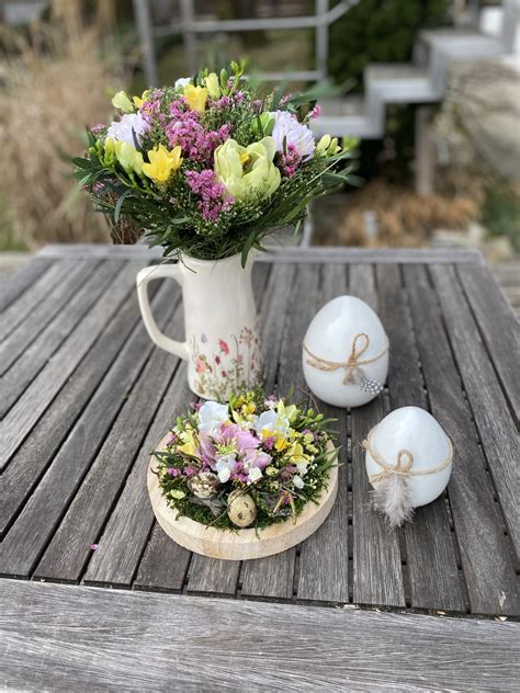 Jarný aranžmán na stole s kvetmi a pastelovými doplnkami.