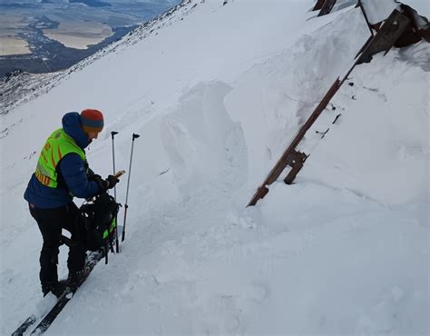 Ilustrácia skialpinistu v akcii, s batohom a lyžami na chrbte v zasneženom teréne