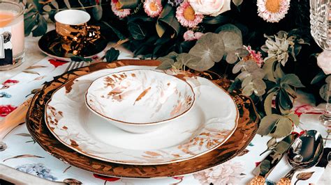 elegantné stolovanie s bielymi tanierikmi so zlatým lemom a zlatými svietnikmi