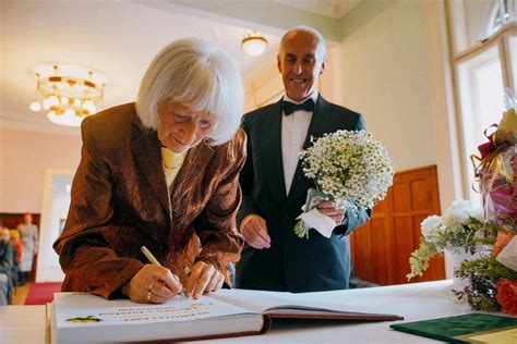 Pár v seniorskom veku, oslavujúci zlatú svadbu, držiaci sa za ruky so zlatými obrúčkami