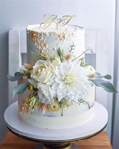 Torta s modrou stužkou a elegantnými bielymi kvetmi.