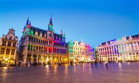 Panoramatický pohľad na vysvietené námestie Grand Place v Bruseli s dominantným vianočným stromčekom a historickými cechovými domami