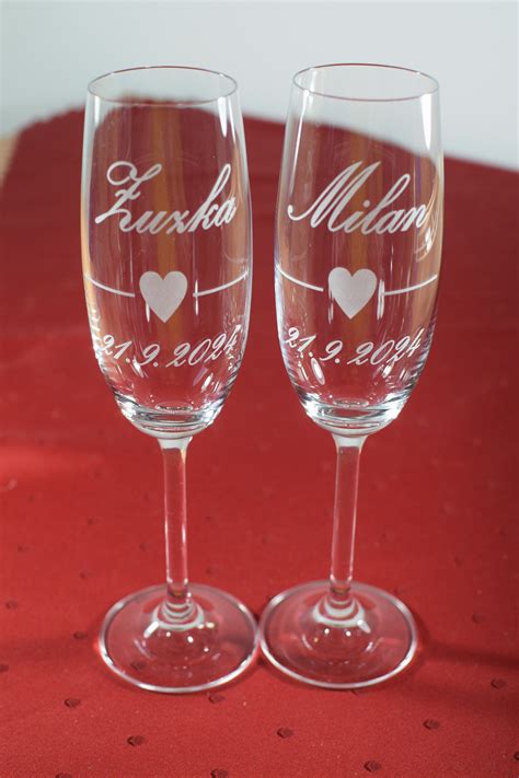 Detailná fotografia dvoch zdobených svadobných pohárov s vygravírovanými menami mladomanželov