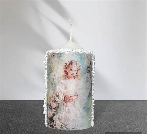 Papierový anjelik umiestnený okolo sviečky v pohári